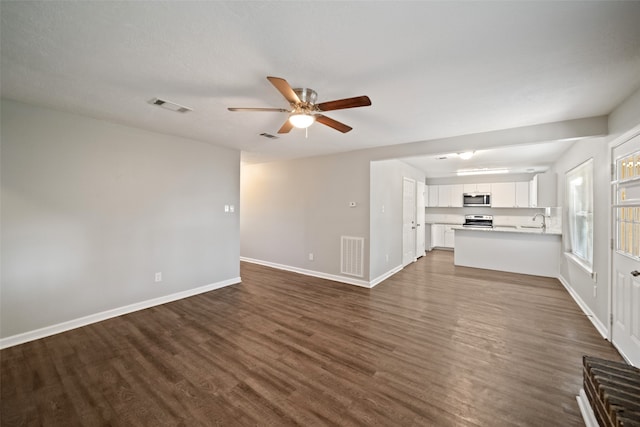 unfurnished living room with dark hardwood / wood-style flooring, sink, and ceiling fan