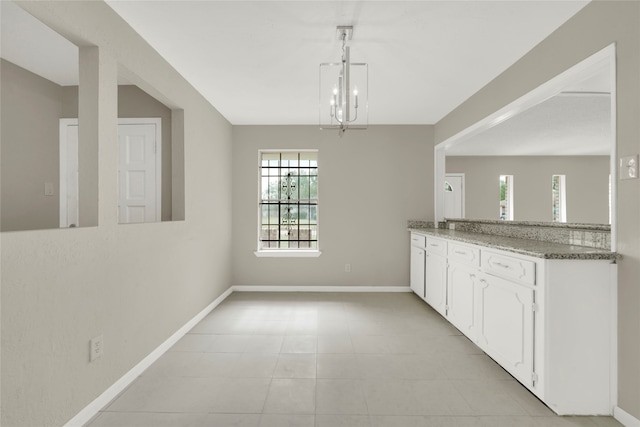 kitchen with pendant lighting, white cabinetry, a chandelier, and light tile patterned floors