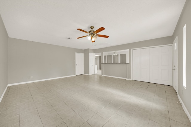 interior space featuring a textured ceiling, a closet, ceiling fan, and light tile patterned floors