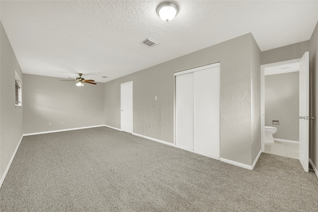 unfurnished bedroom with ceiling fan, connected bathroom, a textured ceiling, and carpet floors