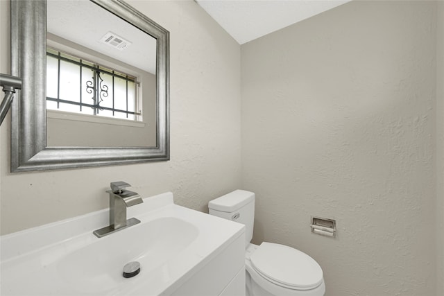 bathroom featuring vanity, toilet, and vaulted ceiling