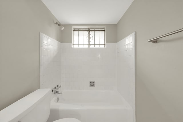 bathroom with tiled shower / bath combo and toilet