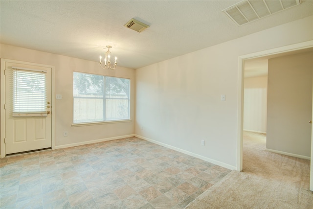 unfurnished room featuring a textured ceiling and an inviting chandelier