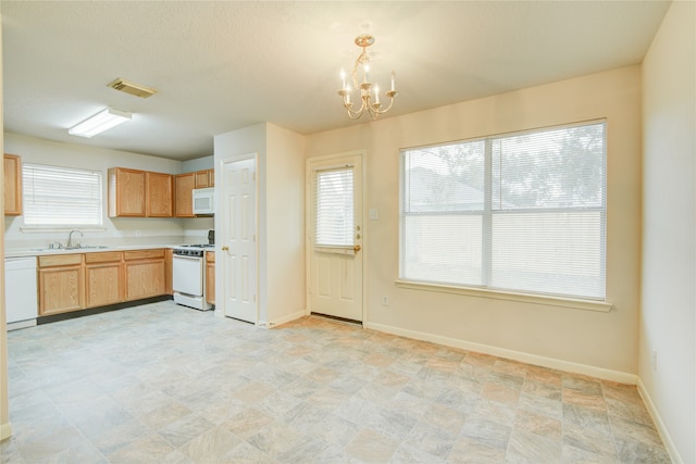 kitchen featuring decorative light fixtures, white appliances, sink, and a chandelier