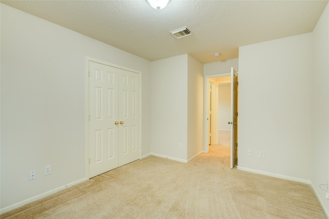 unfurnished room featuring light carpet and a textured ceiling