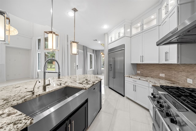 kitchen with white cabinets, sink, high quality appliances, ventilation hood, and decorative light fixtures