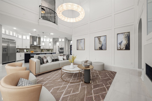 living room with a high ceiling, sink, and light tile patterned floors