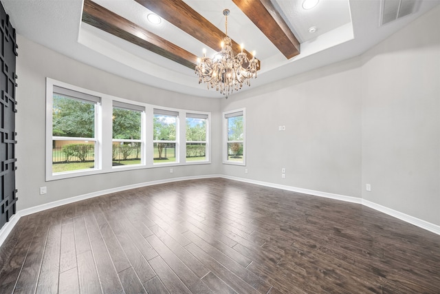 spare room with a barn door, plenty of natural light, dark wood-type flooring, and a notable chandelier