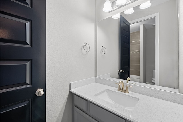 bathroom featuring a tile shower, vanity, and toilet