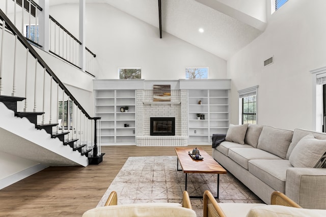 living room with a fireplace, wood-type flooring, a textured ceiling, and high vaulted ceiling