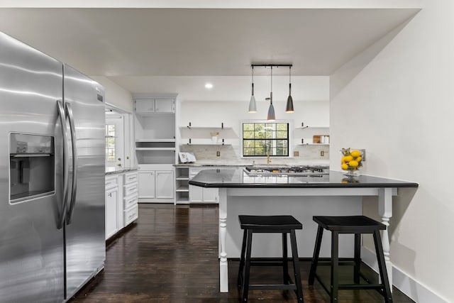 kitchen featuring white cabinetry, a breakfast bar, kitchen peninsula, appliances with stainless steel finishes, and pendant lighting