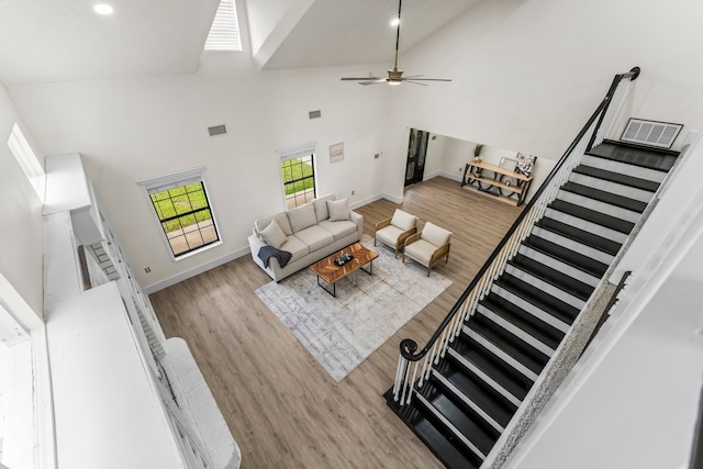 living room with light hardwood / wood-style floors, ceiling fan, and high vaulted ceiling