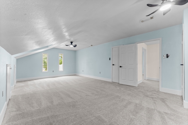 additional living space featuring a textured ceiling, light carpet, ceiling fan, and vaulted ceiling