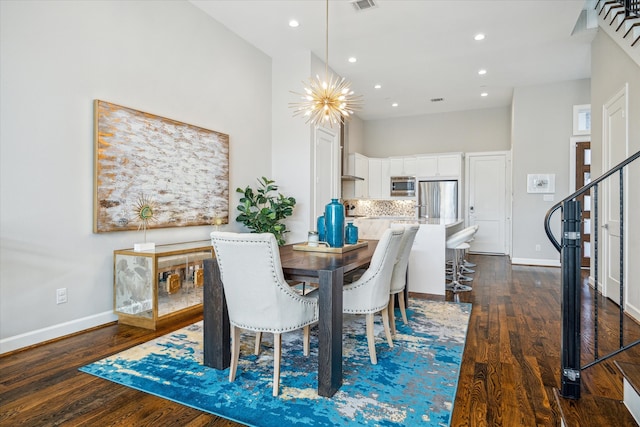 dining area with dark hardwood / wood-style flooring, a notable chandelier, and a towering ceiling