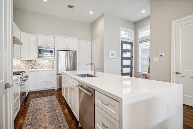 kitchen with stainless steel appliances, white cabinetry, sink, a kitchen island with sink, and dark wood-type flooring