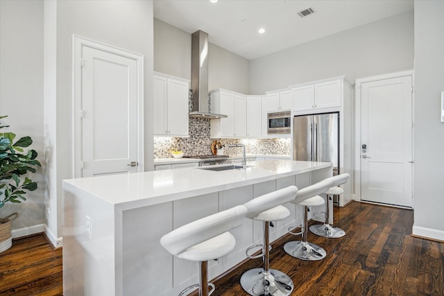 309 W Pierce St, Houston, TX 77019 - kitchen featuring stainless steel appliances, wall chimney exhaust hood, a sink, dark wood finished floors, and a towering ceiling