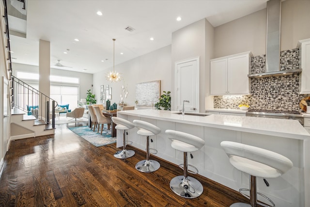 kitchen featuring white cabinetry, sink, wall chimney exhaust hood, a large island, and dark hardwood / wood-style flooring