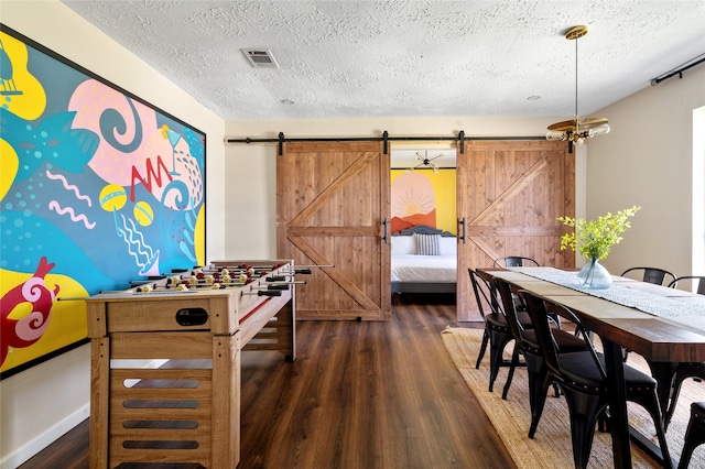 game room with a textured ceiling, dark hardwood / wood-style flooring, and a barn door