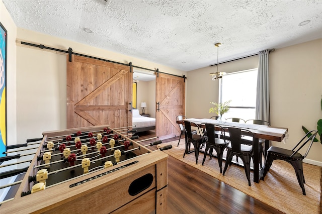 playroom with a barn door, a textured ceiling, and dark hardwood / wood-style flooring