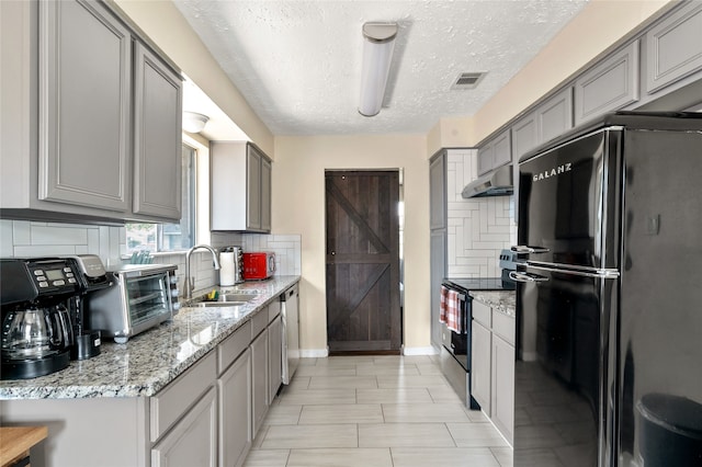 kitchen featuring stainless steel appliances, sink, a textured ceiling, gray cabinetry, and decorative backsplash