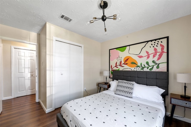 bedroom with a closet, a textured ceiling, and dark hardwood / wood-style floors