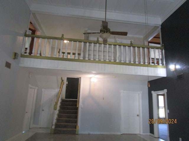 stairs featuring a towering ceiling, ceiling fan, and crown molding