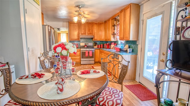 kitchen with decorative backsplash, stainless steel gas stove, light hardwood / wood-style floors, and ceiling fan