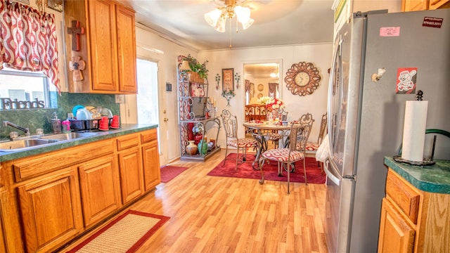 kitchen with stainless steel refrigerator, sink, ceiling fan, light hardwood / wood-style flooring, and decorative backsplash