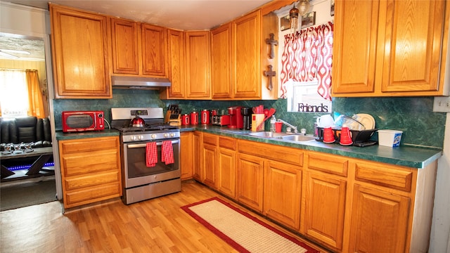 kitchen featuring tasteful backsplash, stainless steel range with gas stovetop, sink, and light hardwood / wood-style flooring