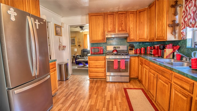 kitchen featuring ornamental molding, backsplash, appliances with stainless steel finishes, ceiling fan, and light hardwood / wood-style flooring