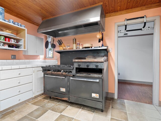 kitchen featuring white cabinetry, tile counters, light hardwood / wood-style floors, wood ceiling, and extractor fan