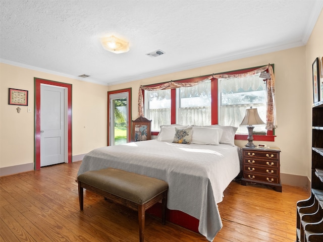 bedroom with a textured ceiling, hardwood / wood-style flooring, and crown molding