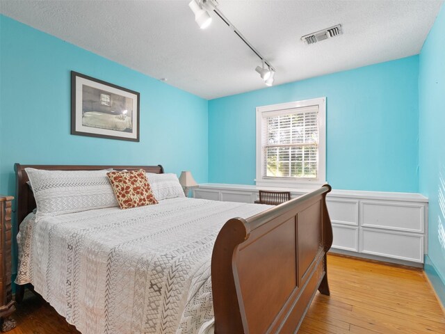 bedroom featuring a textured ceiling, light hardwood / wood-style floors, and track lighting