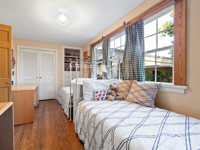 bedroom featuring a textured ceiling, dark wood-type flooring, and a closet