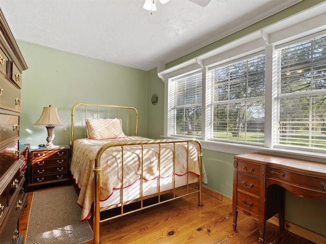 bedroom with ceiling fan, wood-type flooring, and a textured ceiling