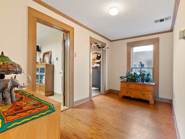 hallway with hardwood / wood-style floors, a textured ceiling, and ornamental molding