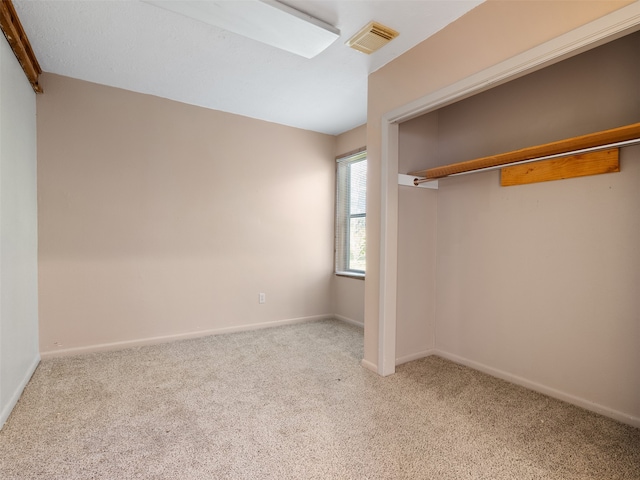 unfurnished bedroom featuring light colored carpet and a closet