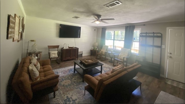 living room featuring a textured ceiling, dark hardwood / wood-style flooring, ceiling fan, and crown molding