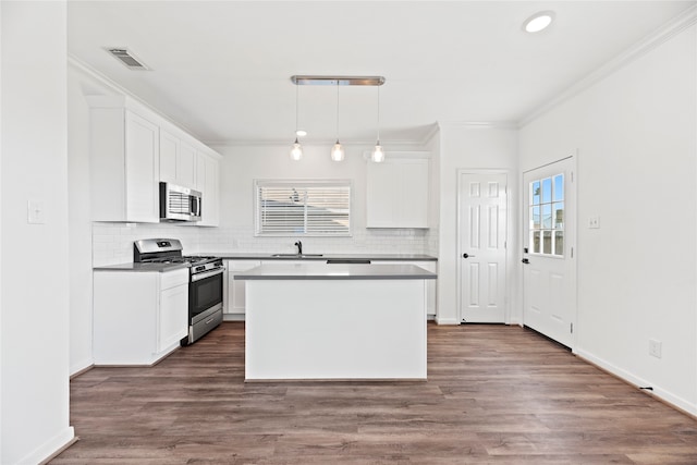 kitchen featuring pendant lighting, stainless steel appliances, white cabinetry, and a kitchen island