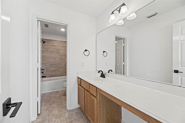 full bathroom featuring toilet, vanity, tiled shower / bath, and tile patterned flooring