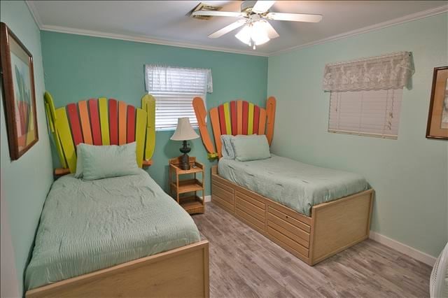 bedroom featuring ceiling fan, light wood-type flooring, and crown molding