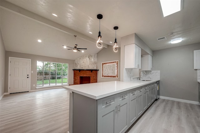 kitchen with light wood-type flooring, kitchen peninsula, sink, and vaulted ceiling with beams