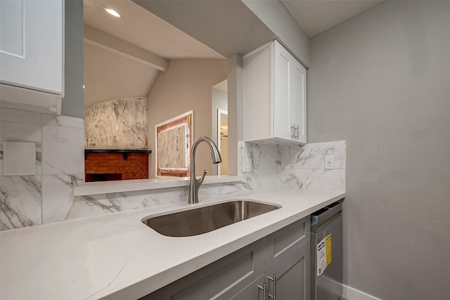 kitchen featuring tasteful backsplash, white cabinetry, sink, vaulted ceiling, and dishwasher