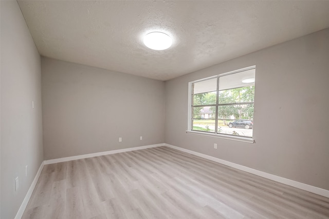 spare room featuring a textured ceiling and light hardwood / wood-style flooring