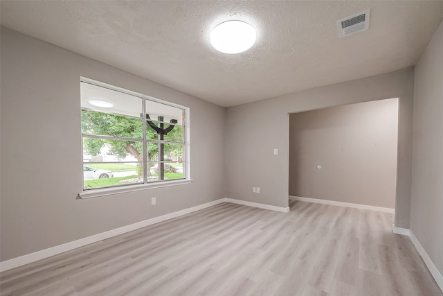 spare room with light hardwood / wood-style floors and a textured ceiling