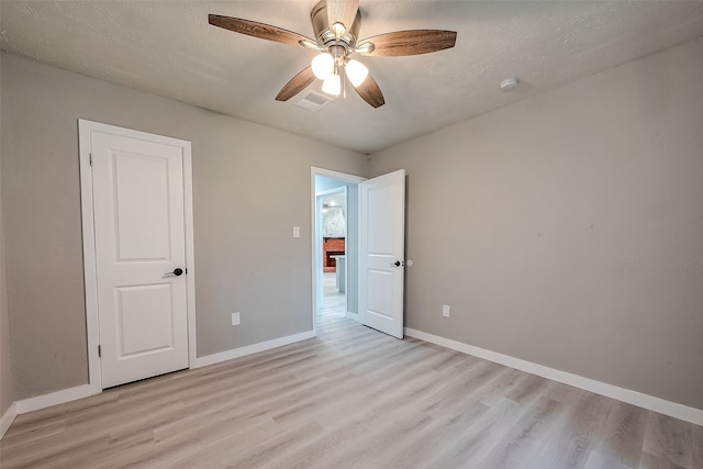 empty room featuring a textured ceiling, light hardwood / wood-style flooring, and ceiling fan