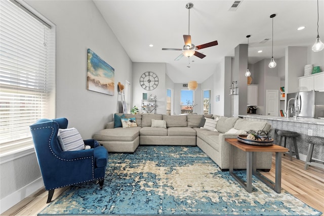 living room with light hardwood / wood-style floors, lofted ceiling, and ceiling fan