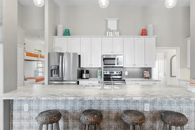 2423 Sandpiper, Crystal Beach, TX 77650 - kitchen with appliances with stainless steel finishes, a breakfast bar, and white cabinets