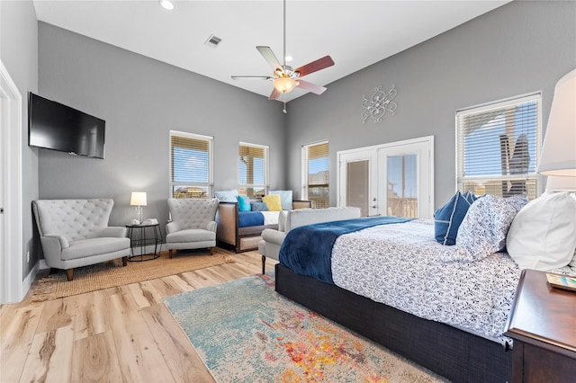 bedroom with french doors, hardwood / wood-style floors, a towering ceiling, and ceiling fan