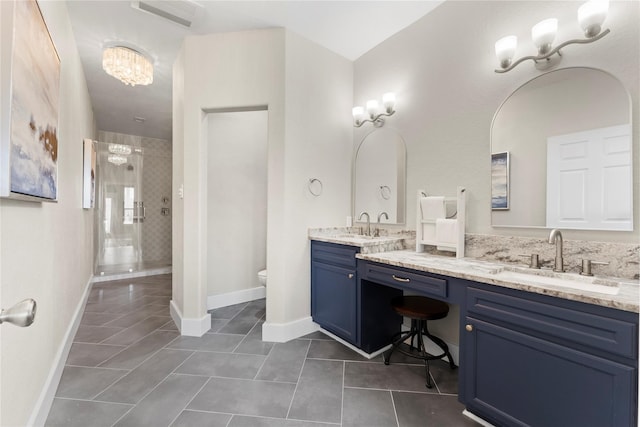 bathroom featuring toilet, tile patterned flooring, a notable chandelier, a tile shower, and vanity